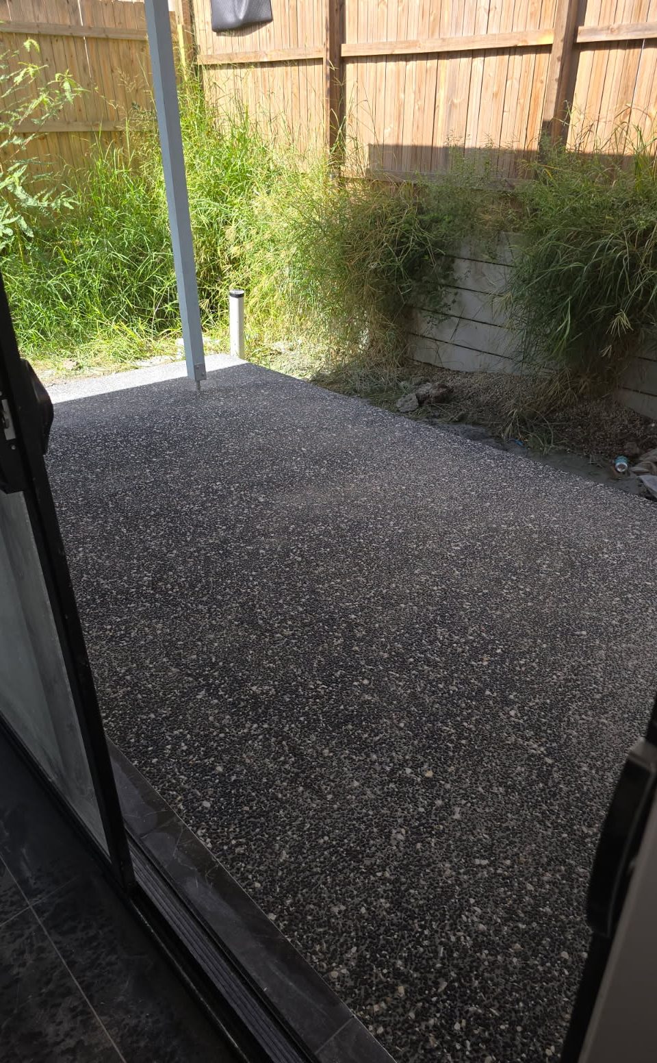 Dark salt and pepper exposed aggregate alfresco slab under a covered outdoor area